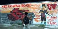 Homem imita gesto com dois dedos, o V, antes “de vitória” ou “paz e amor”, agora também associado ao Comando Vermelho (CV).  Foto: 